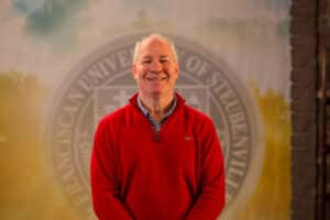 Dr. Donald Kissinger standing in front of a university seal.