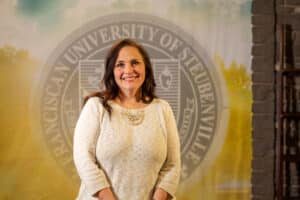 Nicole Hough standing in front of a college seal.